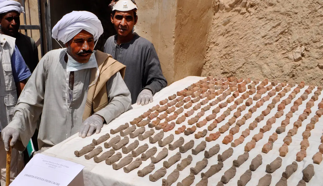 Arkeolog Mesir mengamati Ushabti (patung ukiran kecil) yang ditemukan di sebuah pemakaman berumur 3.500 tahun, di Kota Luxor selatan, Selasa (18/4). Beberapa koleksi pot tanah liat, tembikar dalam berbagai bentuk dan ukiran ikut ditemukan. (STRINGER/AFP)