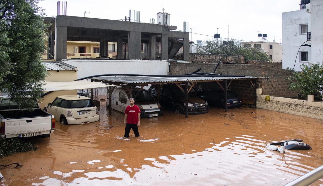 Warga berdiri di area parkir yang terendam banjir setelah hujan lebat di desa Malia, pulau Kreta, Yunani, Selasa (10/11/2020). Banjir besar di Pulau Kreta Yunani merusak jalan, membanjiri ratusan rumah, dan menyeret mobil ke laut di tengah hujan deras yang sedang berlangsung. (AP Photo/Harry Nakos)