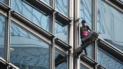Alain Robert yang dijuluki 'French Spiderman' memanjat gedung pencakar langit Cheung Kong Center di Hong Kong, Jumat (16/8/2019). Selama pendakian, Alain Robert memasang spanduk yang menampilkan bendera Hong Kong dan China. (Lillian SUWANRUMPHA/AFP)