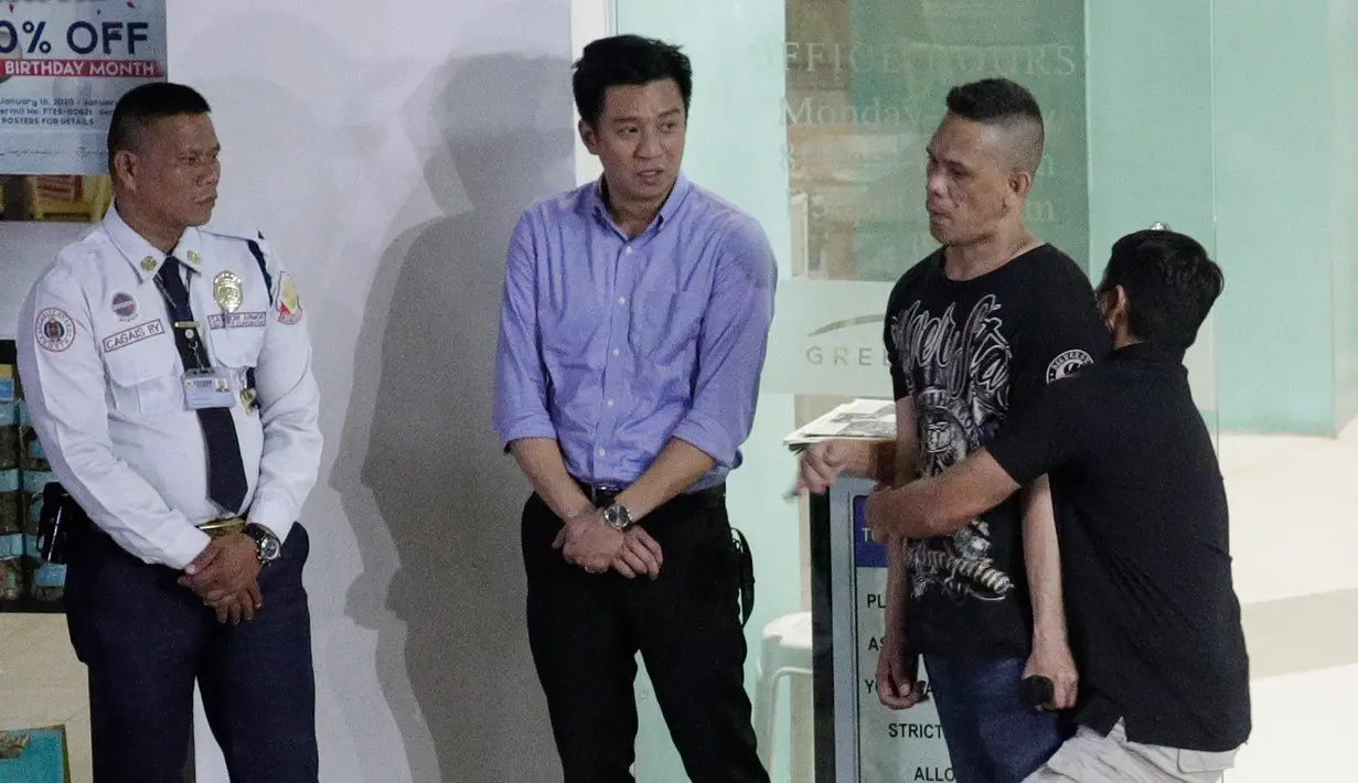 Polisi mendekap pelaku penyenderaan Alchie Paray (kanan) saat sedang berbicara kepada awak media di V-Mall, Manila, Filipina, Senin (2/3/2020). Mantan penjaga mal tersebut menyerahkan diri setelah 10 jam menyendera 30 orang. (AP Photo/Aaron Favila)