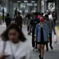 Seorang wanita berjalan mengenakan masker pelindung untuk menghindari polusi udara buruk di Jakarta, Rabu (17/7/2019). Dinkes DKI menyarankan masyarakat untuk menggunakan masker saat beraktivitas untuk mencegah dampak polusi udara pada tubuh. (Liputan6.com/Faizal Fanani)