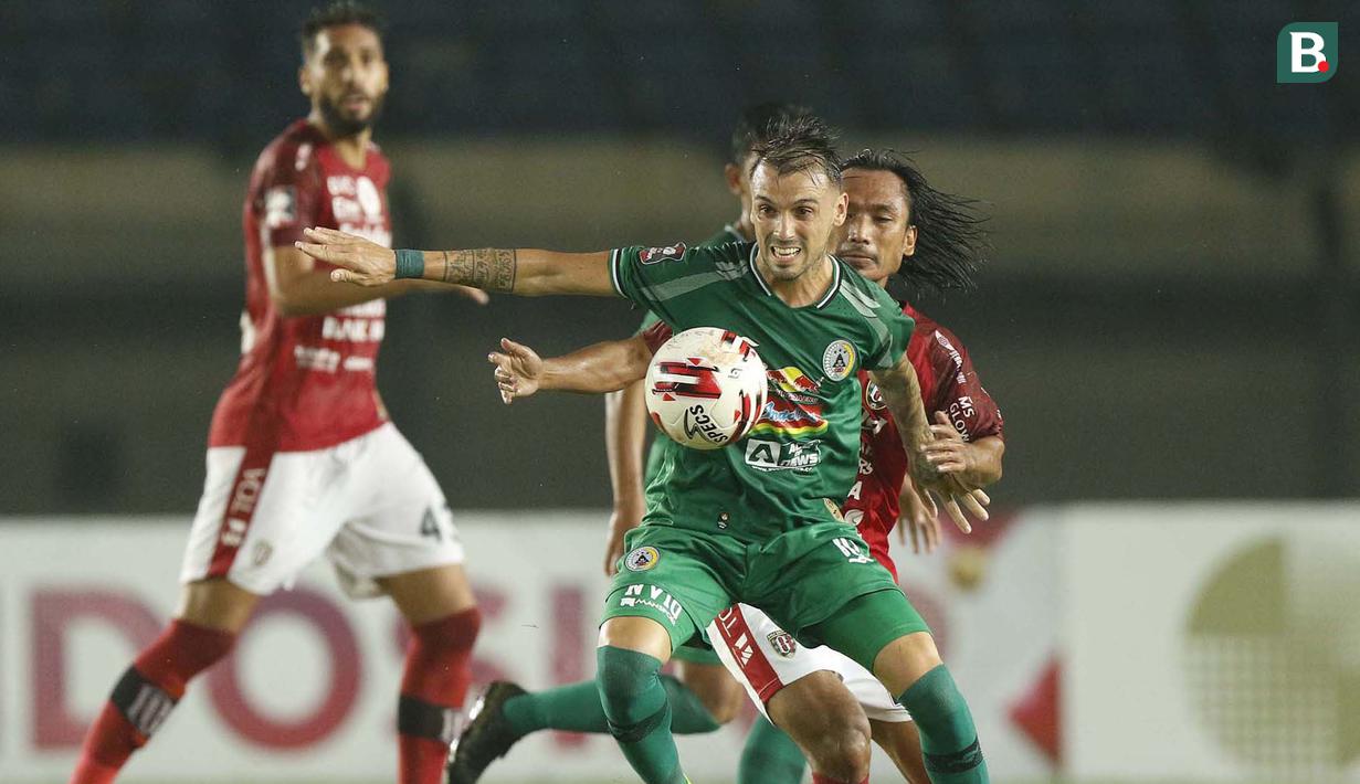 Striker PS Sleman, Velez Nicolas Leandro (depan) mengontrol bola dibayangi gelandang Bali United, Hariono dalam laga perempatfinal Piala Menpora 2021 di Stadion Si Jalak Harupat, Bandung, Senin (12/4/2021). (Bola.com/Ikhwan Yanuar)