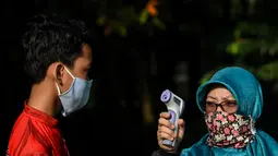 Seorang anak diukur suhu tubuh sebelum latihan memanah yang diadakan SAN Archery Club di Desa Ciater, Tangerang Selatan (9/8/2020). SAN Archery Club dibuka kembali bagi anggotanya untuk berlatih kembali dengan mengikuti protokol kesehatan di tengah wabah COVID-19. (Agung Kuncahya B./Xinhua)