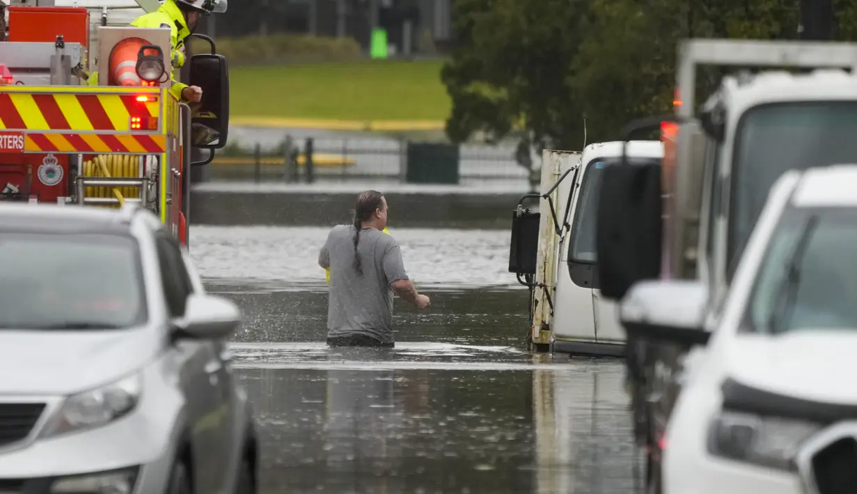 Seorang pria berjalan melalui air banjir kembali ke rumahnya dari sebuah truk pemadam kebakaran di Windsor di pinggiran Sydney, Australia, Selasa (5/6/2022). Ratusan rumah terendam di dalam dan sekitar kota terbesar Australia itu dalam keadaan darurat banjir yang berdampak pada 50.000 orang, kata para pejabat. (AP Photo/Mark Baker)