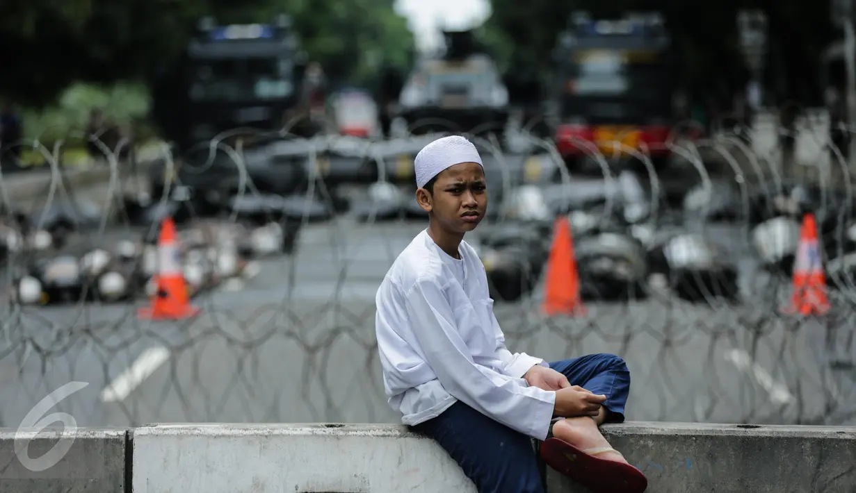 Peserta aksi duduk disekitar kawat berduri saat aksi bela islam 313 di Jalan Merdeka Barat, Jakarta, Jumat (31/3). Mereka menuntut kepada Presiden Jokowi agar melaksanakan undang-undang dengan mencopot gubernur terdakwa, Ahok. (Liputan6.com/Faizal Fanani)