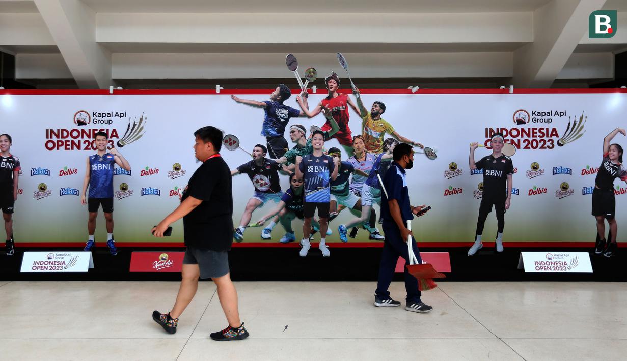 <p>Sejumlah pekerja sedang melintasi foto booth di Istora Senayan menjelang Indonesia Open 2023 pada Senin (12/06/2023). Ketua Panpel Armand Darmadji mengungkapkan bahwa tahun ini akan menjadi edisi terakhir turnamen BWF Super 1000 tersebut di Istora Senayan sebelum dipindahkan ke arena yang lebih besar yakni Indoor Multifunction Stadium. (Bola.com/Bagaskara Lazuardi)</p>