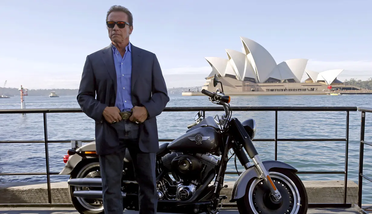 Arnold Schwarzenegger menggunakan kacamata sambil berpose di samping motor Harley saat mempromosikan film terbarunya, `Terminator Genisys` di depan Sydney Opera House di Australia, Kamis (4/6/2015). (REUTERS/David Gray)