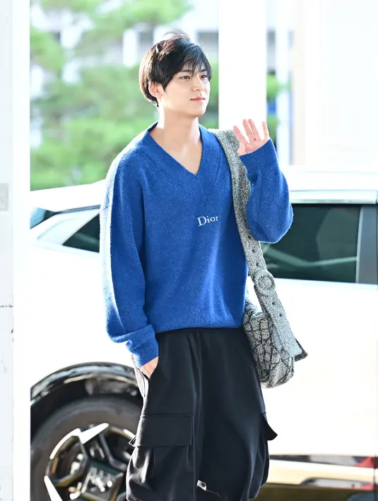 Ia mengenakan sweater knit biru dengan celana pendek kargo berwarna hitam [Dior]