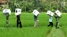 Petugas Kelompok Penyelenggara Pemungutan Suara (KPPS) membawa logistik Pemilu 2019 melintasi sawah menuju TPS di Desa Cidokom, Bogor, Selasa (16/4). Pada 17 April 2019, masyarakat dapat menunaikan haknya mencoblos, baik untuk memilih caleg maupun presiden-wakil presiden. (Merdeka.com/Arie Basuki)