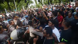 Massa driver taksi online yang tergabung dalam Aliando terlibat aksi saling dorong dengan polisi saat menggelar demo di Jalan Medan Merdeka Barat, Jakarta, Rabu (28/3). Dalam aksinya mereka sempat bersitegang dengan polisi. (Merdeka.com/Imam Buhori)