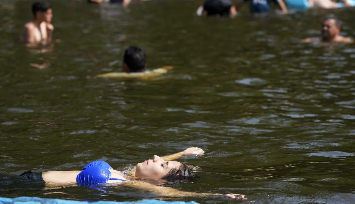 Orang-orang mendinginkan tubuh di danau di tengah gelombang panas di Paraguari, Paraguay, Minggu (16/1/2022). Suhu Paraguay secara umum mencapai 41 derajat celsius. (AP Photo/Jorge Saenz)