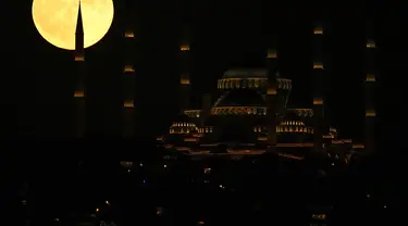 Bulan purnama terbit di belakang masjid Camlica di Istanbul, Turki, Senin (3/7/2023). Bulan purnama penuh yang dijuluki Buck Moon yang muncul pada 3 Juli menjadi supermoon pertama tahun ini. (AP Photo/Francisco Seco)