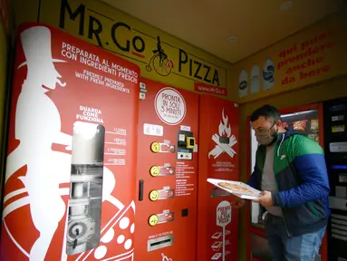 Seorang pria mengambil pesanannya di mesin penjual pizza otomatis, yang pertama dari jenisnya di pusat kota Roma, pada 29 April 2021. Mesin penjual otomatis ini mampu menguleni adonan, membumbui, memasak, dan menyajikan pizza dalam kotak karton hanya dalam waktu tiga menit. (Filippo MONTEFORTE/AFP)