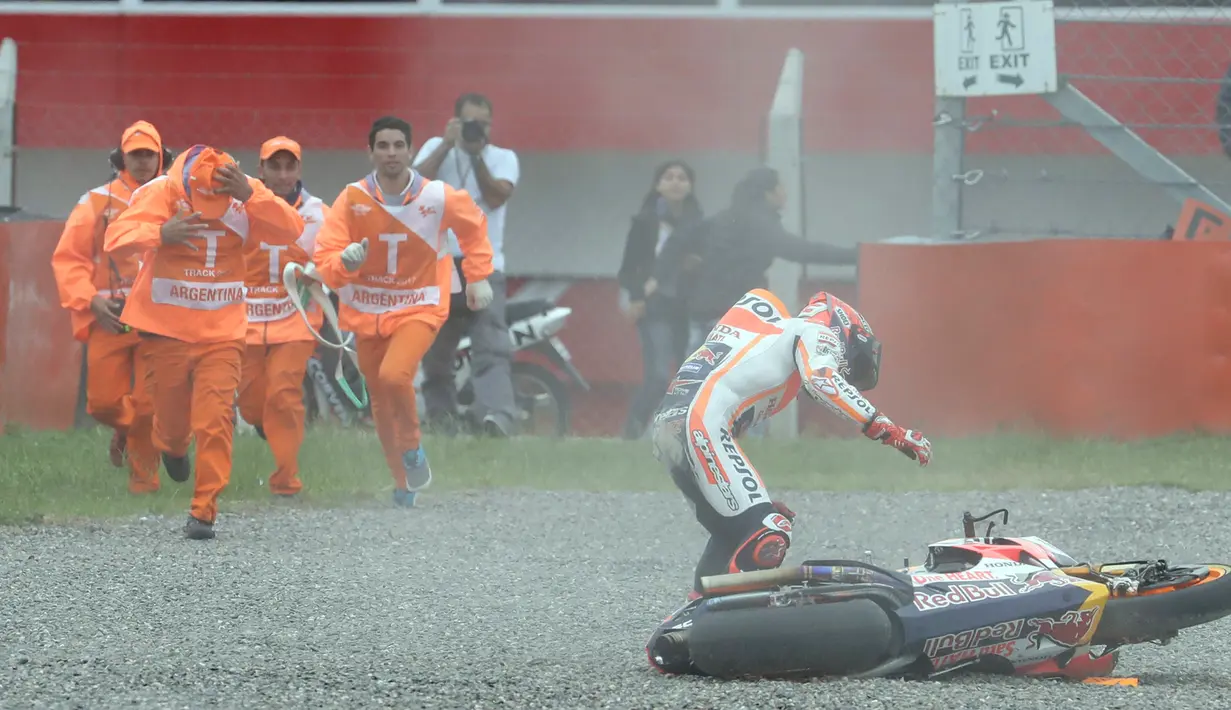 Marc Marquez berusaha mendirikan kembali motornya usai terpental dari lintasan saat berlaga di Grand Prix Argentina, Minggu (9/4). Marc Marquez hilang kendali saat hendak menikung ke kiri. (AP Photo/ Natacha Pisarenko)