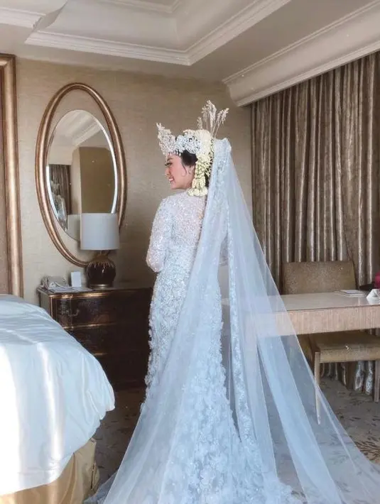 Penampilannya dilengkapi dengan kain batik, siger, roncean melati, serta veil panjang hingga menyapu lantai.