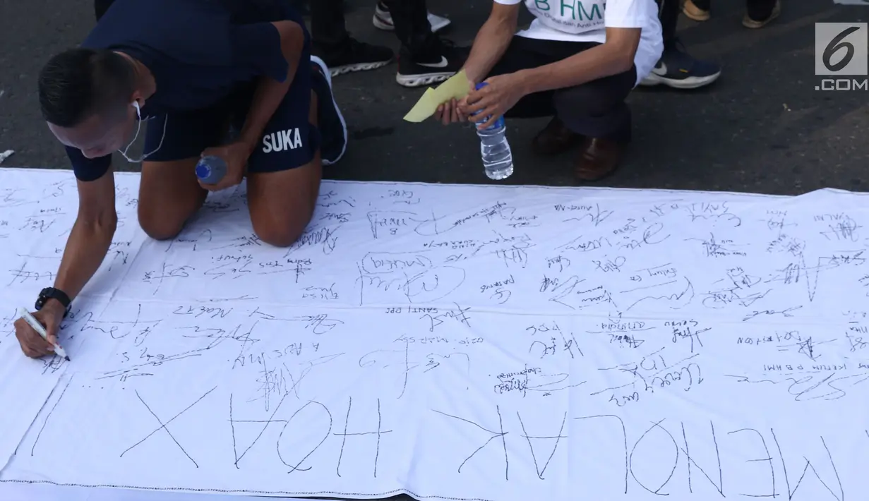 Warga menandatangani spanduk dukungan anti hoax di kawasan Bundaran Hotel Indonesia, Jakarta, Minggu (18/11). PB HMI mensosialisasikan Hoax sebagai ancaman demokrasi di Indonesia. (Liputan6.com/Helmi Fithriansyah)
