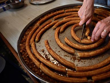 Seorang wanita menyiapkan potongan churros di toko churreria kuno yang didirikan pada tahun 1872 di Pamplona, Spanyol, Senin (10/7/2023). Churros merupakan sarapan khas selama berlangsungnya Festival San Fermin. (AP Photo/Alvaro Barrientos)