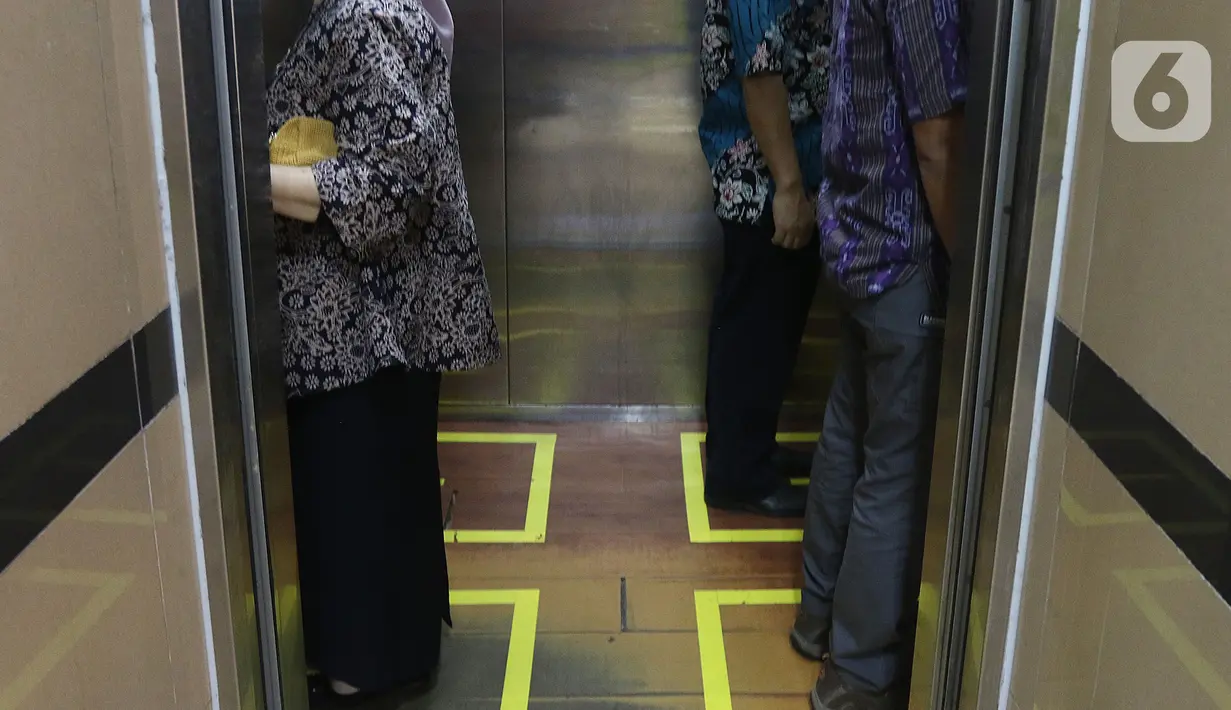 Sejumlah orang menaiki lift yang telah dipasangi garis batas dan saling membelakangi di PMI DKI Jakarta, Jumat (20/3/2020). PMI DKI Jakarta memberlakukan disiplin saling menjaga jarak atau social distancing sebagai langkah untuk mengantisipasi penyebaran COVID-19. (Liputan6.com/Herman Zakharia)