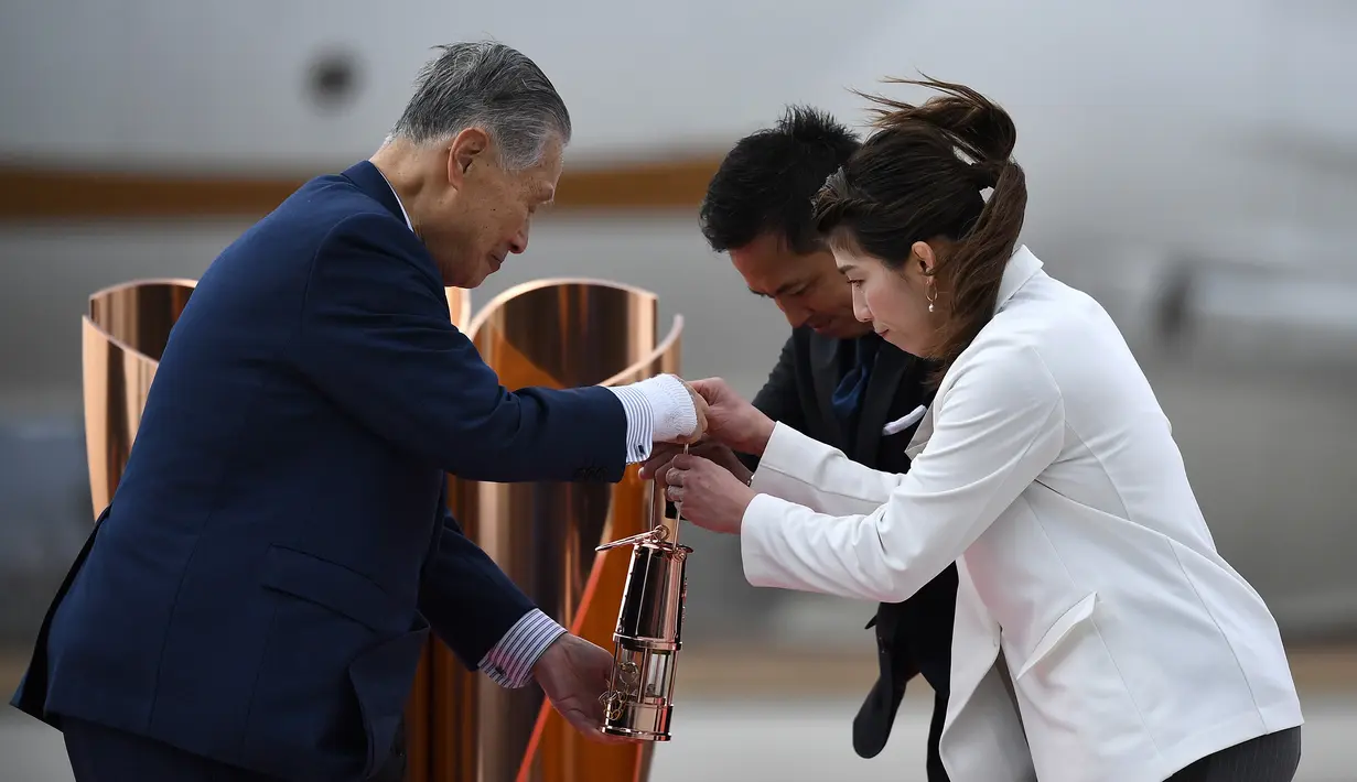 Presiden Olimpiade Tokyo 2020, Yoshiro Mori, menerima api Olimpiade saat tiba dari Yunani di Pangkalan Udara Matsushima, Jepang, Jumat (20/3). Di tengah pandemi virus corona Covid-19, prosesi menuju Olimpiade Tokyo 2020. (AFP/Philip Fong)