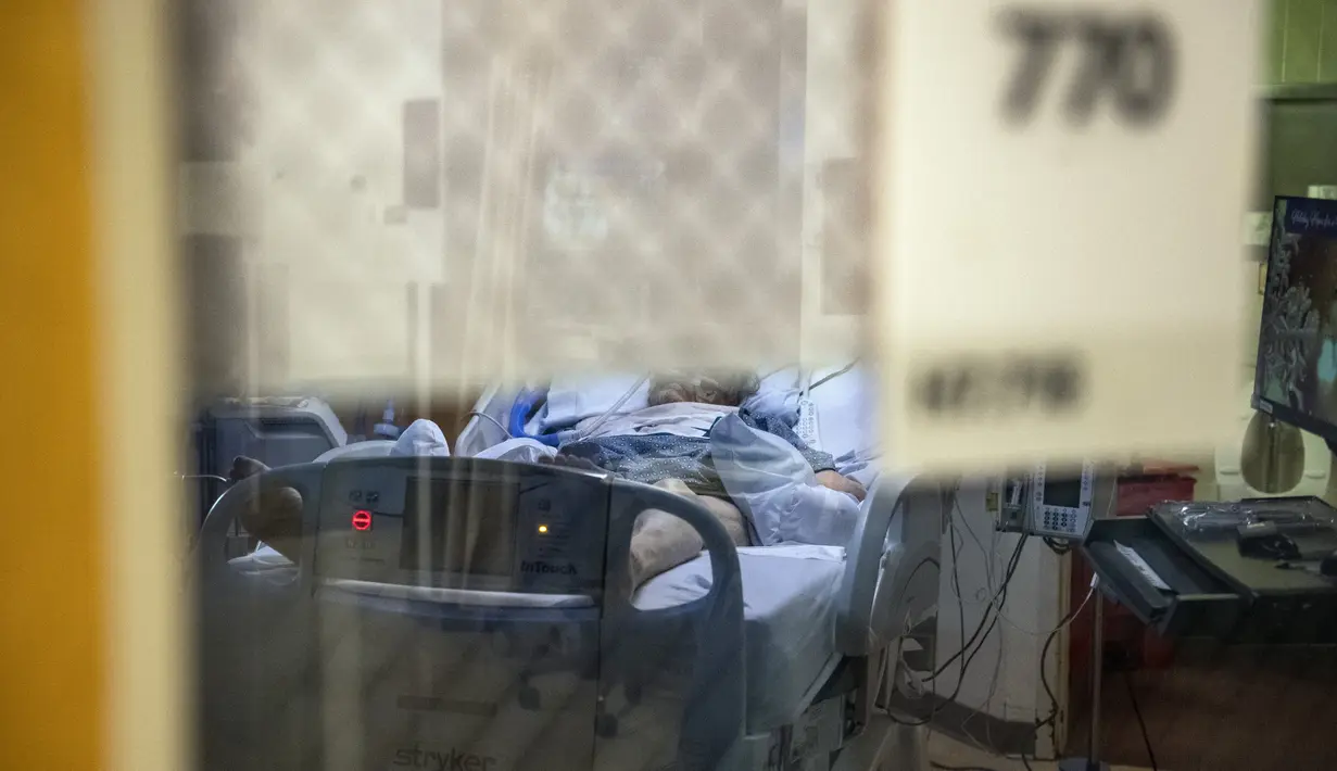 Seorang pasien terinfeksi Covid-19 duduk di tempat tidur di ruang tekanan negatif di bangsal ICU UMass Memorial Medical Center di Worcester, Massachusetts, Selasa (4/1/2022). Rumah sakit mengklaim mereka dipenuhi pasien dan tidak memiliki banyak tempat tidur tersisa jika ada. (Joseph Prezioso/AFP)