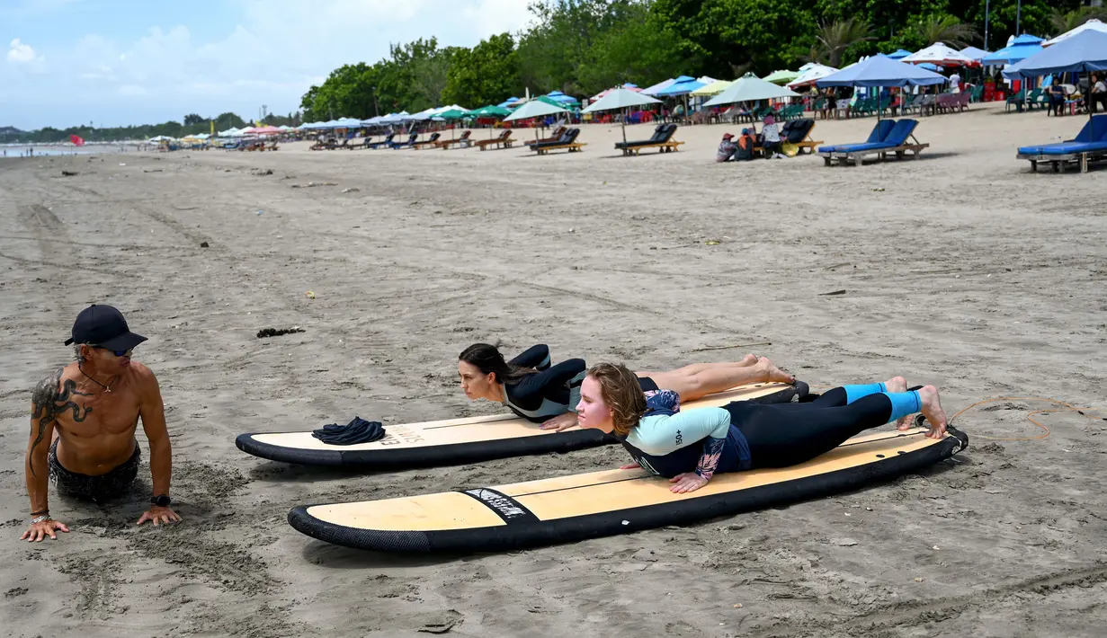 <p>Seorang instruktur memberi contoh teknik berselancar di pantai Kuta, Bali, pada 8 Desember 2023. (SONNY TUMBELAKA/AFP)</p>