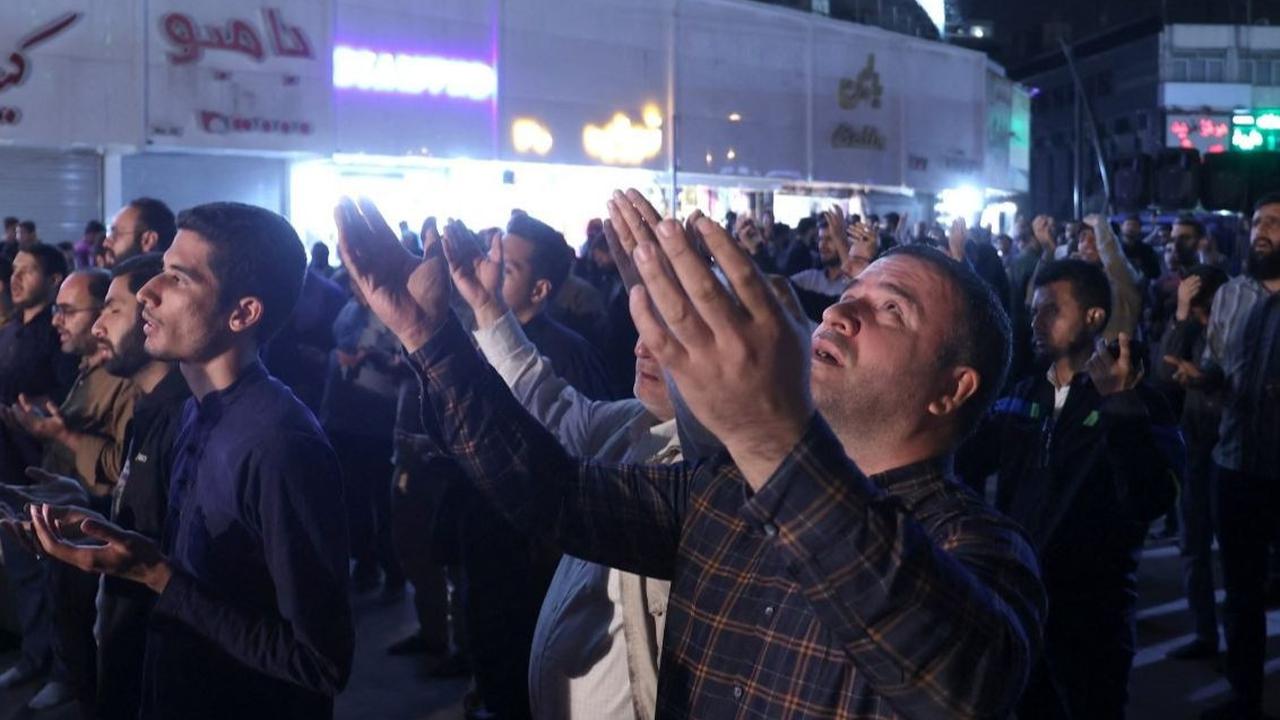Para warga Iran mengangkat kedua tangan mereka saat menanjatkan doa untuk keselamatan Presiden Iran Ebrahim Raisi dan Menteri Luar Negeri Hossein Amir-Abdollahian yang dilaporkan berada dalam helicopter yang jatuh di pegunungan di Lapangan Valiasr, pusat 