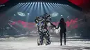 Model Irina Shayk melenggang ditemani robot sambil membawakan koleksi desainer Philipp Plein dalam New York Fashion Week 2018, Sabtu (10/2). Robot warna hitam yang bentuknya menyerupai Transformers itu lalu berjalan di sepanjang catwalk  (AP/Craig Ruttle)