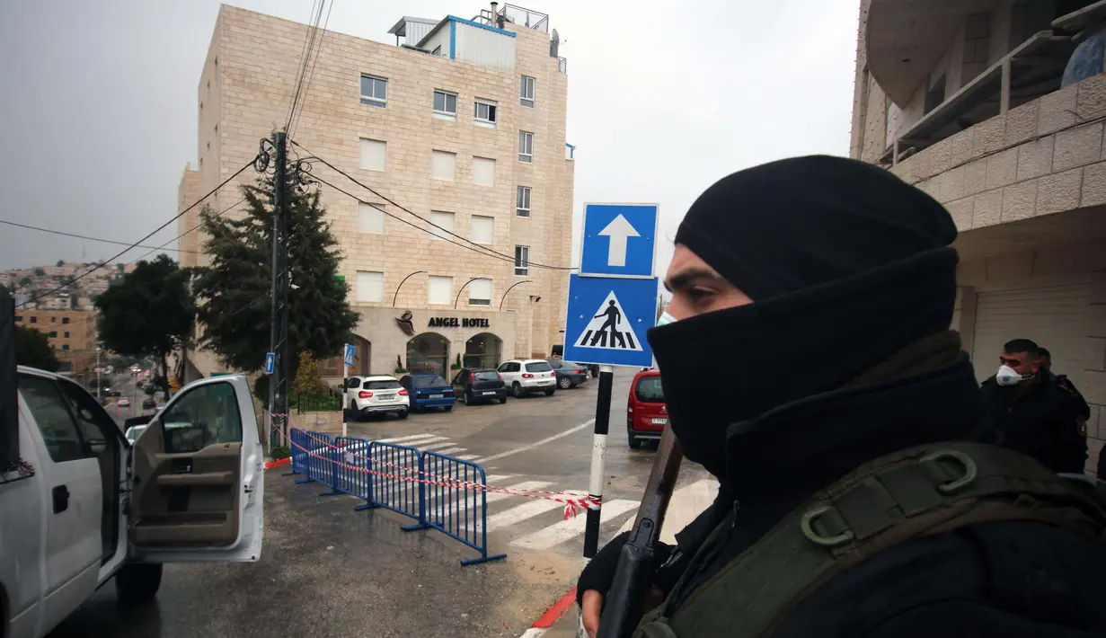 Dengan mengenakan masker, seorang aparat kepolisian Palestina berjaga-jaga di luar Angel Hotel di Kota Betlehem, Tepi Barat, pada 6 Maret 2020. Keadaan darurat mulai diberlakukan pada Jumat (6/3) di Palestina di tengah kekhawatiran penyebaran coronavirus baru. (Xinhua/Stringer)