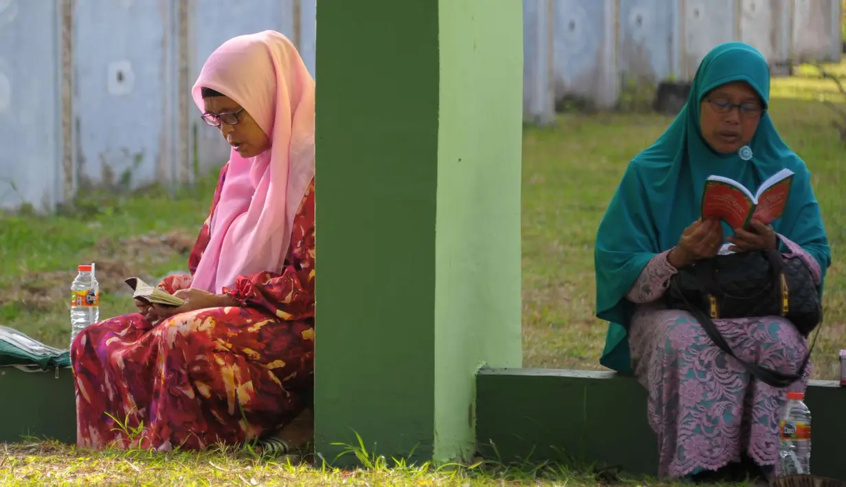 Warga Aceh berdoa di pemakaman massal Ulhee Lheue, Banda Aceh, Sabtu (26/12/2015).  Doa tersebut untuk keluarga mereka yang terkena bencana Tsunami pada 26 Desember 2014. (AFP Photo/ Chaideer Mahyuddin)