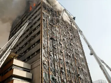 Petugas pemadam menggunakan crane mobil damkar untuk memadamkan kebakaran gedung tertua Iran, gedung Plasco, di pusat kota Teheran, Kamis (19/1). Sedikitnya 38 orang terluka akibat kebakaran di Gedung Plasco yang ikonik tersebut. (AFP PHOTO/STR)