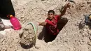 Seorang anak laki-laki menggali kuburan di pemakaman Wadi al-Salam, di Najaf, selatan Baghdad, Irak. 27 Juli 2016. Sejumlah kuburan banyak yang rusak akibat perang yang terjadi di Irak. (REUTERS/Alaa Al-Marjani)