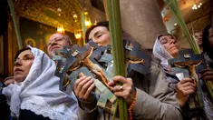 Jemaat Katolik Roma memegang daun palem dan gambar Yesus selama prosesi Minggu Palma di Gereja Makam Kudus, Kota Tua Yerusalem, Minggu (25/3). Gereja ini diyakini sebagai tempat penyaliban dan penguburan Yesus Kristus. (AP Photo/Oded Balilty)