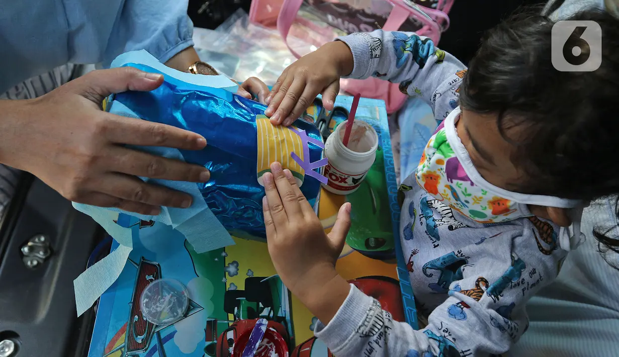 Siswa TK didampingi guru membuat miniatur bedug saat mengikuti proses pembelajaran secara Drive in Learning di area parkir Padepokan Pencak Silat Indonesia, Jakarta, Kamis (8/4/2021). Kegiatan ini untuk mengenalkan bulan suci Ramadan kepada anak-anak sedari dini. (Liputan6.com/Herman Zakharia)