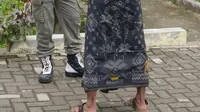 Seorang pengendara bercelana pendek mengenakan kain sarung yang diberikan polisi Syariat Islam saat razia penertiban hukum syariat islam di Banda Aceh, Aceh, Selasa (19/9). Razia itu digelar oleh Satpol PP dan Wilayatul Hisbah. (CHAIDEER MAHYUDDIN/AFP)