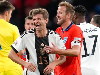 Pemain Jerman Thomas Muller tertawa dengan pemain Inggris Harry Kane pada akhir pertandingan sepak bola UEFA Nations League di Stadion Wembley, London, Inggris, 26 September 2022. Pertandingan berakhir imbang 3-3. (AP Photo/Kirsty Wigglesworth)