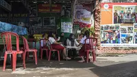 Seorang perempuan dari organisasi pemuda setempat membantu siswa bersekolah secara virtual di tempat pembuangan sampah yang menyediakan WiFi gratis, di Surabaya, Rabu (15/9/2021). Belajar secara virtual itu sudah berjalan lebih dari setahun lebih di tengah pandemi Covid-19. (JUNI KRISWANTO/AFP)