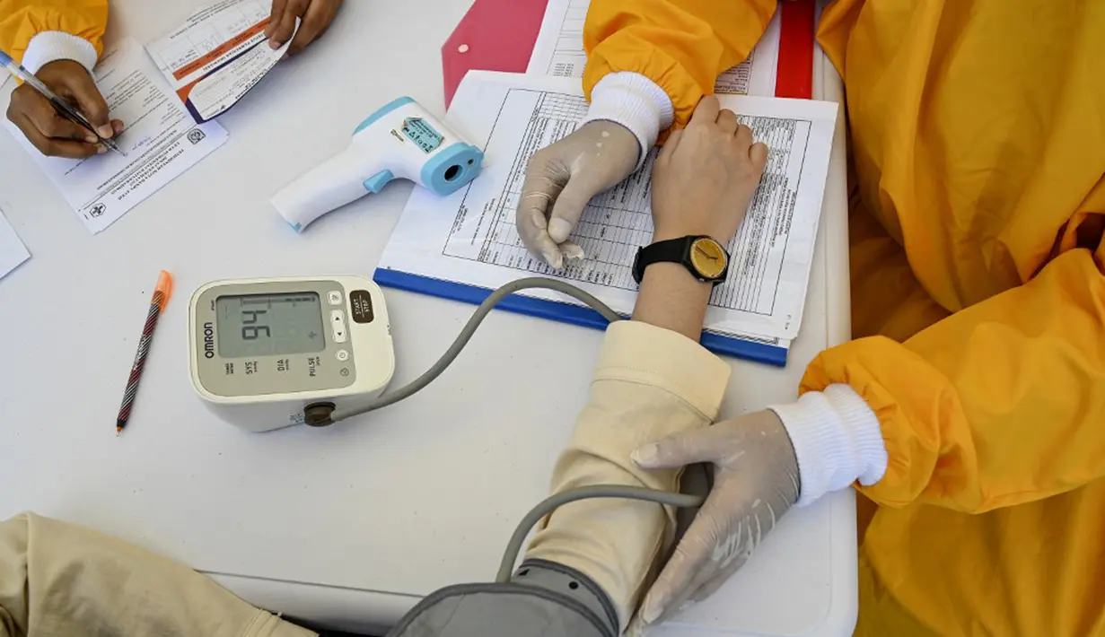 Seorang petugas kesehatan memeriksa tekanan darah seorang wanita sebelum memberinya vaksin virus corona COVID-19 Sinovac saat pelaksanaan vaksinasi di Masjid Raya Baiturrahman, Banda Aceh, Aceh, Selasa (7/9/2021). (CHAIDEER MAHYUDDIN/AFP)