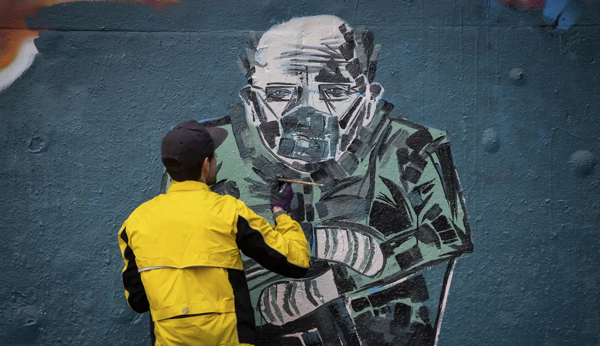 Kevin Belyk melukis mural foto Senator AS Bernie Sanders yang memakai jaket musim dingin dan sarung tangan serta masker wajah pada pelantikan Presiden Joe Biden di taman skateboard Terowongan Leeside di Vancouver, British Columbia (28/1/2021). (Darryl Dyck/The Canadian Press via AP)