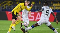 Penyerang Borussia Dortmund, Erling Braut Haaland, berebut bola dengan bek Club Brugge, Odilon Kossounou, pada laga lanjutan Liga Champions di Signal Iduna Park, Rabu (25/11/2020) dini hari WIB. Borussia Dortmund menang 3-0 atas Club Brugge. (AFP/Ina Fassbender)