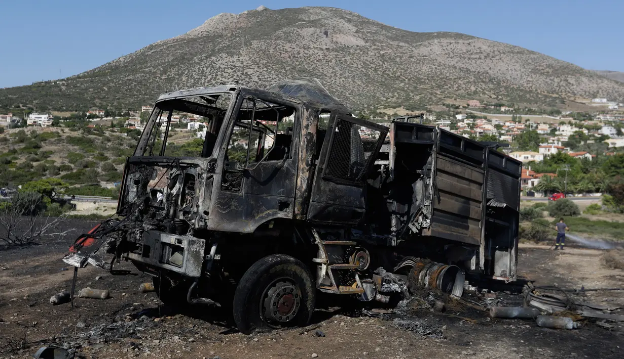 Sebuah mobil pemadam kebakaran hangus dalam kebakaran lahan yang melanda dekat Kalyvia, Yunani, Kamis (3/8). Puluhan petugas dan mobil pemadam kebakaran dikerahkan dalam operasi pemadaman kebakaran besar tersebut. (AP/Thanassis Stavrakis)