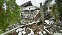 Pemandangan umum menunjukkan bangunan runtuh di Mamuju sehari setelah gempa bumi magnitudo 6,2 mengguncang Sulawesi Barat, Sabtu (16/1/2021). Petugas Badan Penanggulangan Bencana Daerah (BPBD) masih mendata jumlah kerusakan dan korban akibat gempa bumi tersebut. (Firdaus / AFP)