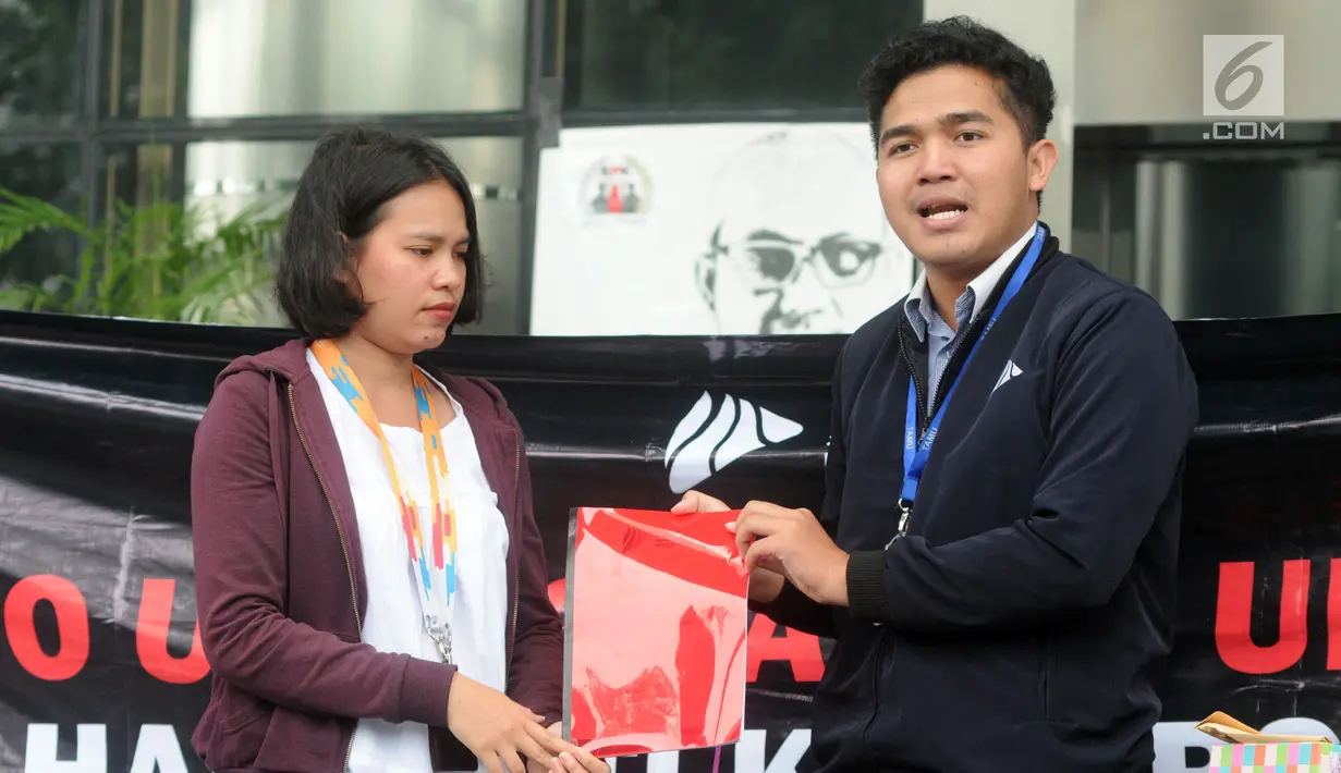 Presiden BEM KM Universitas Gadjah Mada (UGM) Obed Kresna Widyapratistha (kanan) menyerahkan kado buku merah kepada perwakilan Biro Humas KPK Brigita Simbolon pada aksi simpatik di Gedung KPK Jakarta, Senin (10/12). (Merdeka.com/Dwi Narwoko)