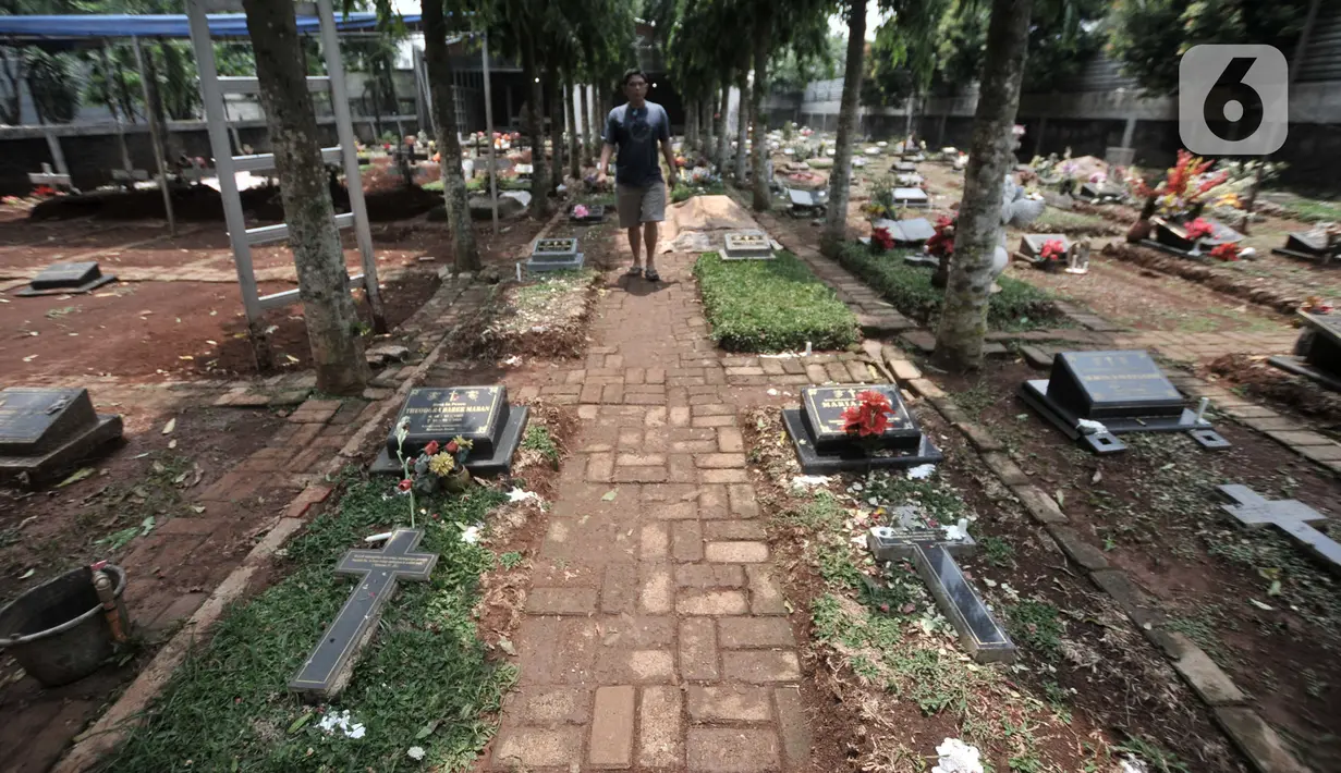 Peziarah melintasi makam yang mengisi sebagian jalan di kompleks pemakaman Paroki Gereja St Servatius, Kampung Sawah, Bekasi, Jawa Barat, Kamis (26/12/2019). (merdeka.com/Iqbal Nugroho)