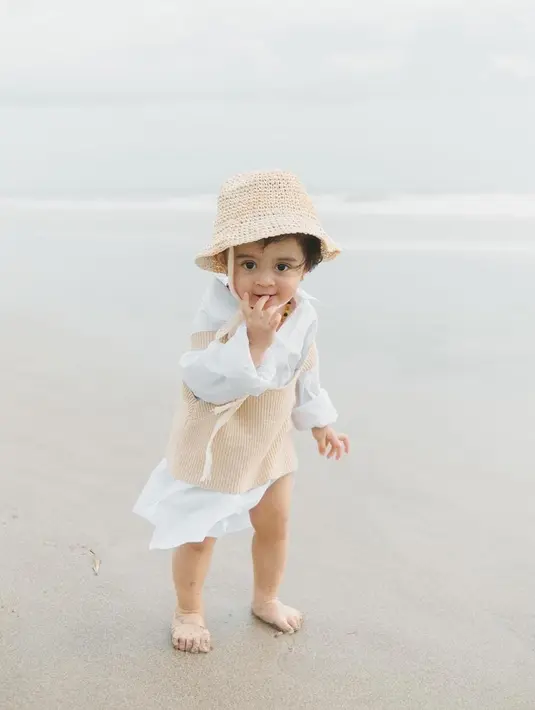 Ini dia potret terbaru putri Ali Syakieb, Guzelim Arcelli saat berlibur di pantai dengan ootd yang tak kalah seperti mama dan ayahnya [Instagram/guzelimalisyakieb]