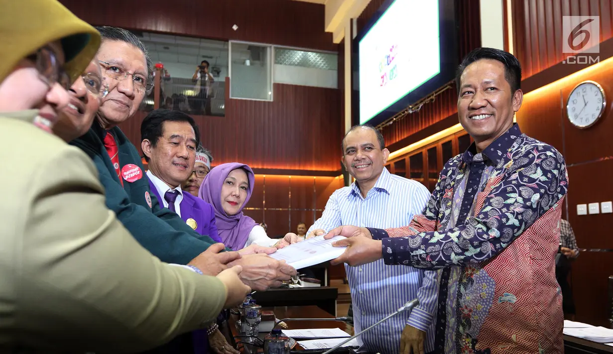 Ketua Umum Ikatan Dokter Indonesia, Oetama Marsis menyerahkan naskah akedemik kepada Ketua Badan Legislasi (Baleg) DPR Supratman Andi Agtas  saat RDPU dengan Badan Legislasi DPR di Kompleks Parlemen, Jakarta, Senin (2/4). (Liputan6.com/JohanTallo)