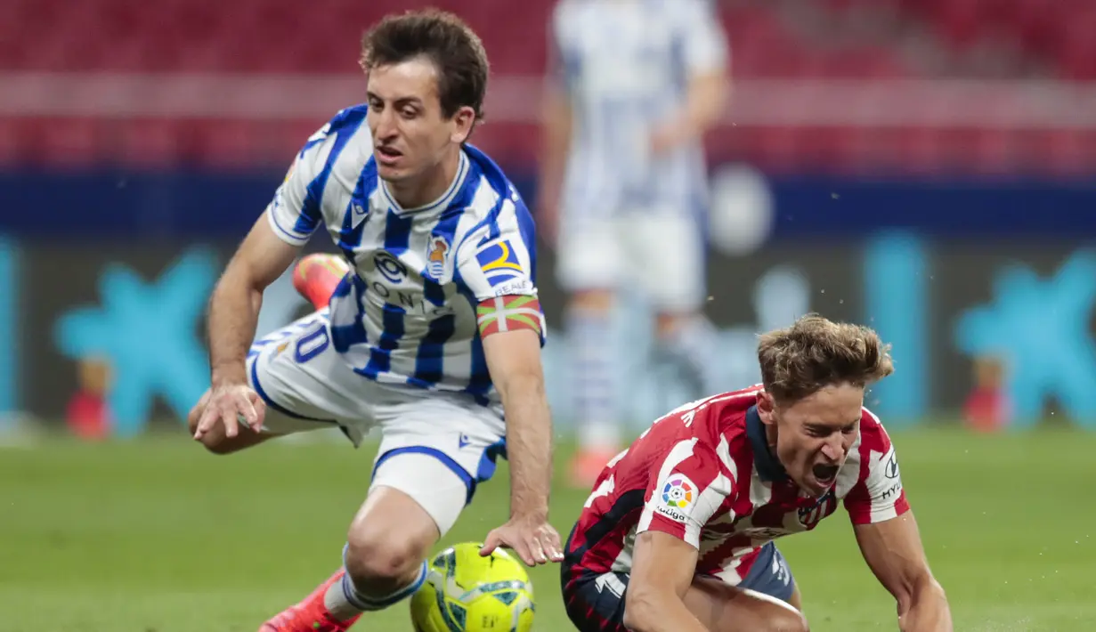 Gelandang Real Sociedad, Mikel Oyarzabal (kiri) dan gelandang Atletico Madrid, Marcos Llorente terjatuh saat perebutan bola dalam laga lanjutan Liga Spanyol 2020/2021 pekan ke-36 di Wanda Metropolitano Stadium, Rabu (12/5/2021). Atletico menang 2-1 atas Sociedad. (AP/Bernat Armangue)