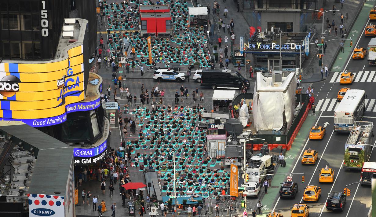 Sejumlah orang melakukan yoga bersama di kawasan Times Square, New York pada 'Summer Solstice' atau hari dengan siang terpanjang di musim panas, Rabu (21/6). Acara tersebut menandai Hari Yoga Internasional yang jatuh pada 21 Juni. (TIMOTHY A. CLARY/AFP)
