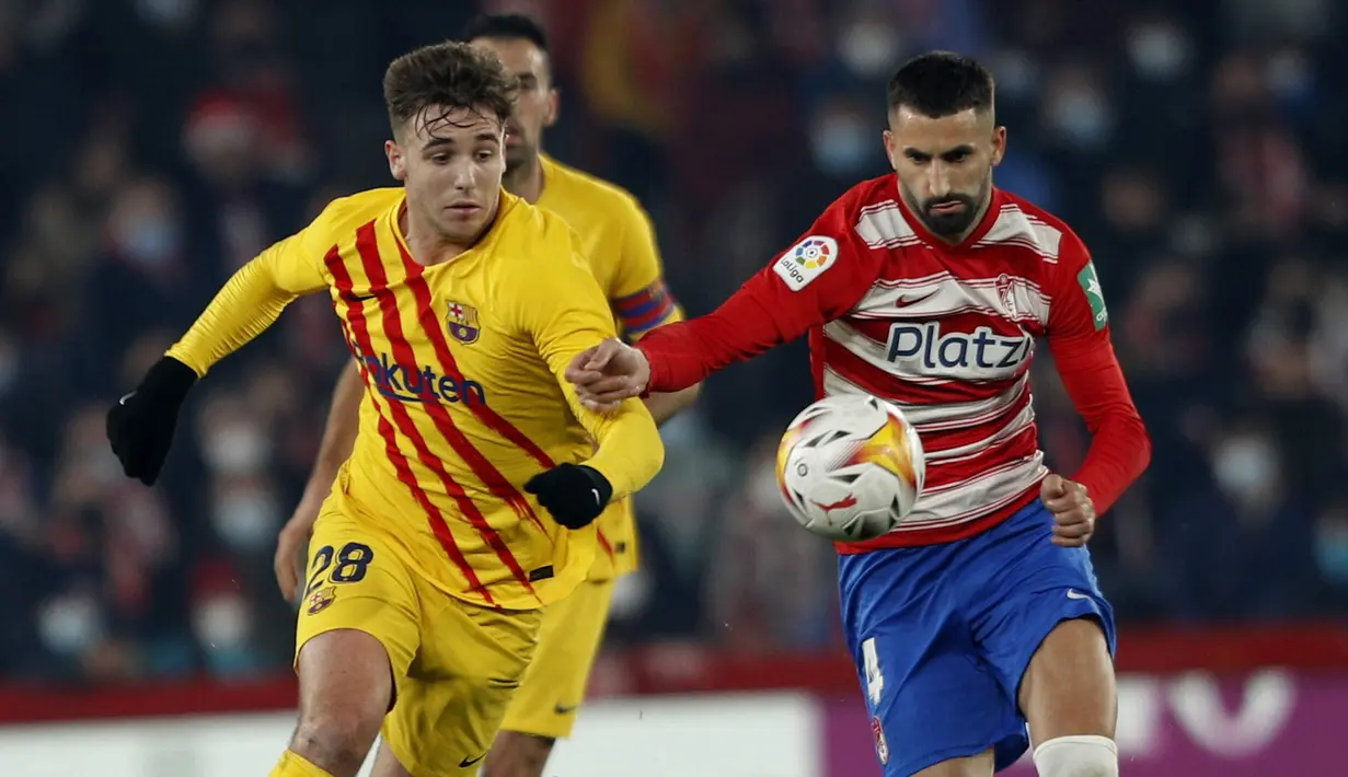 Bek Barcelona Oscar Mingueza berebut bola dengan gelandang Granada Maxime Gonalons dalam jornada ke-20 Liga Spanyol 2021/2022 di Stadion Los Carmenes, Minggu (9/1/2022) dini hari WIB. Barcelona ditahan imbang 1-1 Granada. (AP Photo/Fermin Rodriguez)