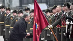 Presiden Ukraina Petro Poroshenko mengambil topi seorang tentara militer saat dia dan Presiden Austria Alexander van der Bellen dalam sebuah upacara penyambutan di Kiev, Ukraina, Rabu, (14/3). (AP Photo / Efrem Lukatsky)