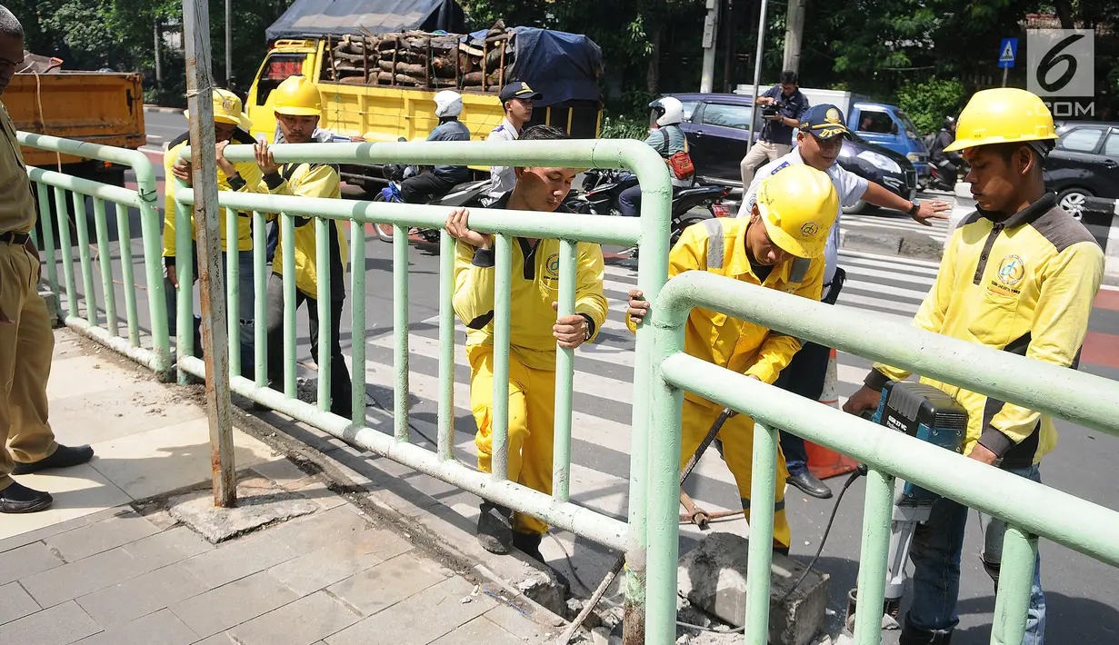 Petugas membongkar pagar pembatas besi di kawasan Pinang Ranti, Jakarta, Senin (11/2). Zebra cross yang berada di samping Tamini Square itu sempat jadi perbincangan lantaran terhalang oleh pagar besi hijau setinggi 1 meter. (Liputan6.com/Herman Zakharia)